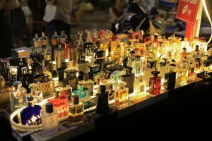 Dziesiątki różnych flakonów perfum podświetlonych na stoisku. Wybór odpowiedniego rodzaju perfum zależy od stężenia olejków zapachowych.