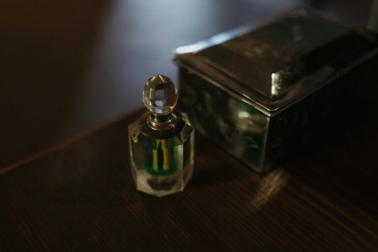 Mały, elegancki flakonik perfum w stylu vintage stojący w półmroku. Dobór odpowiedniego, subtelnego zapachu na uroczystość pogrzebową to wyraz szacunku i taktu.